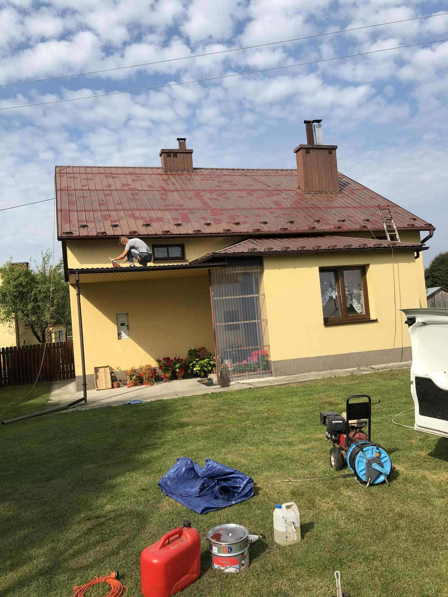 Praca na dachu domu jednorodzinnego podczas malowania