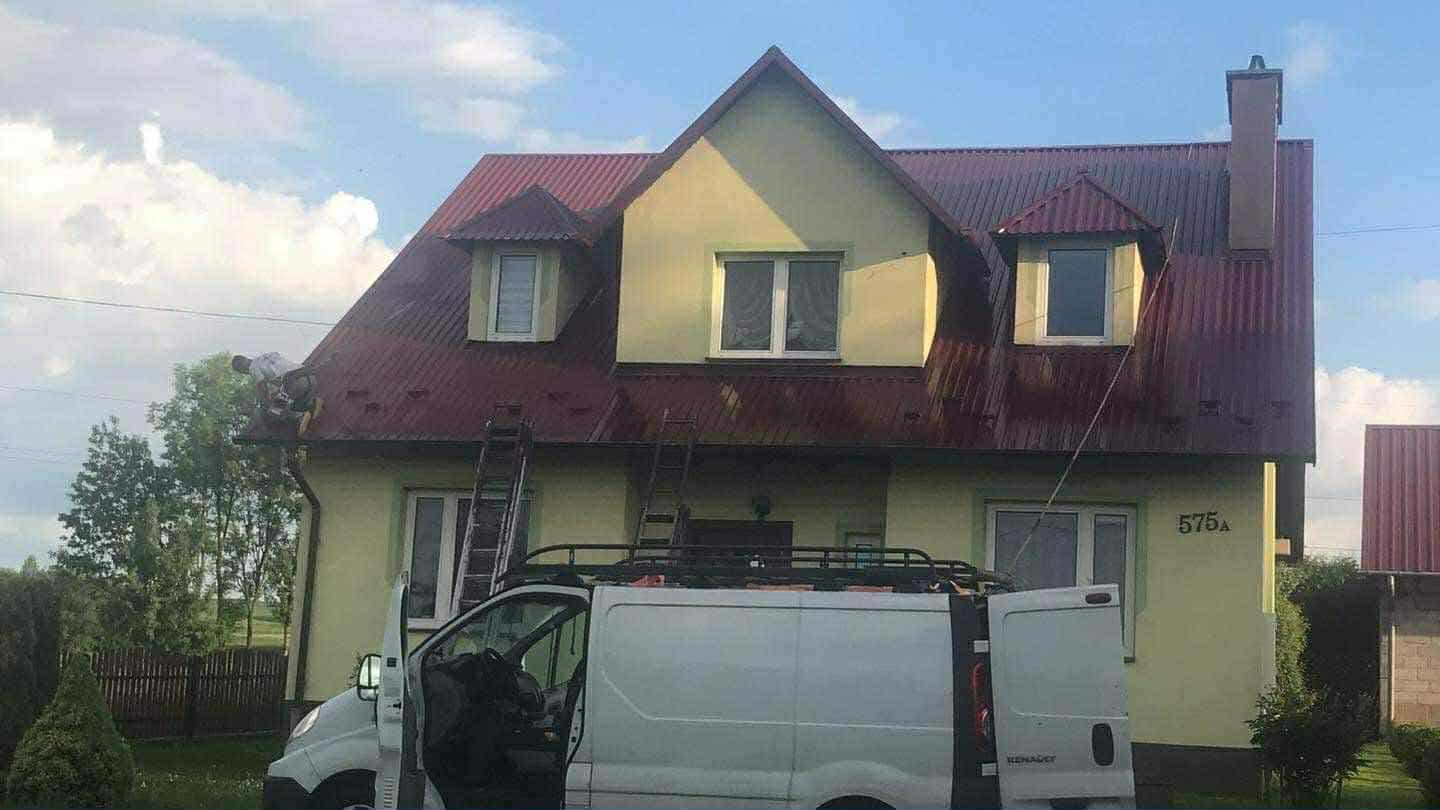 Samochód firmowy przy domu, na którym trwa malowanie dachu